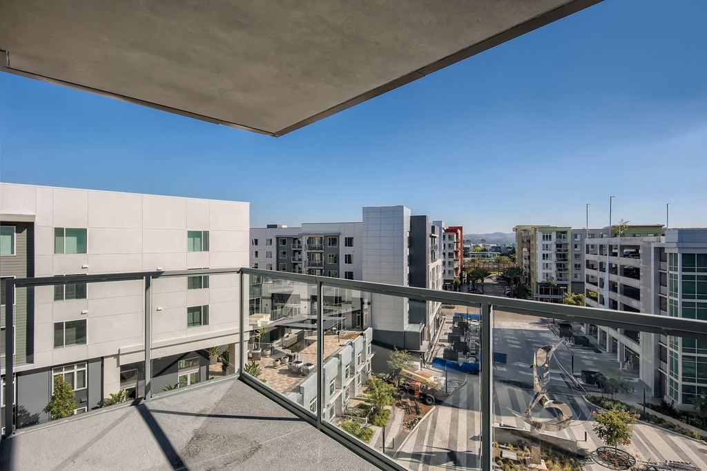 A view from a balcony overlooking a parking lot and buildings.