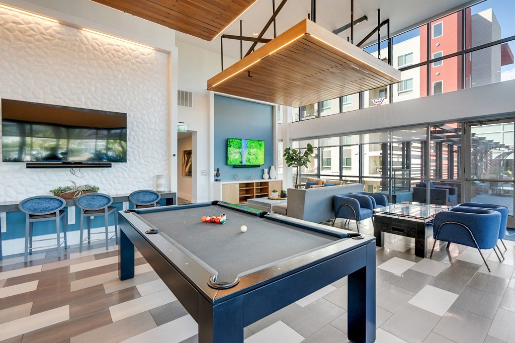 A pool table is in the middle of a room with blue chairs.