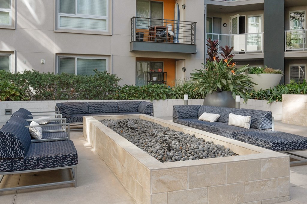 A patio with a couch, chairs, and a fire pit.