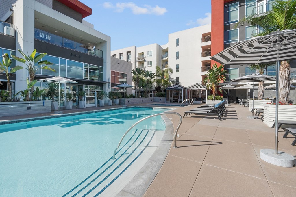 A swimming pool surrounded by lounge chairs and umbrellas.