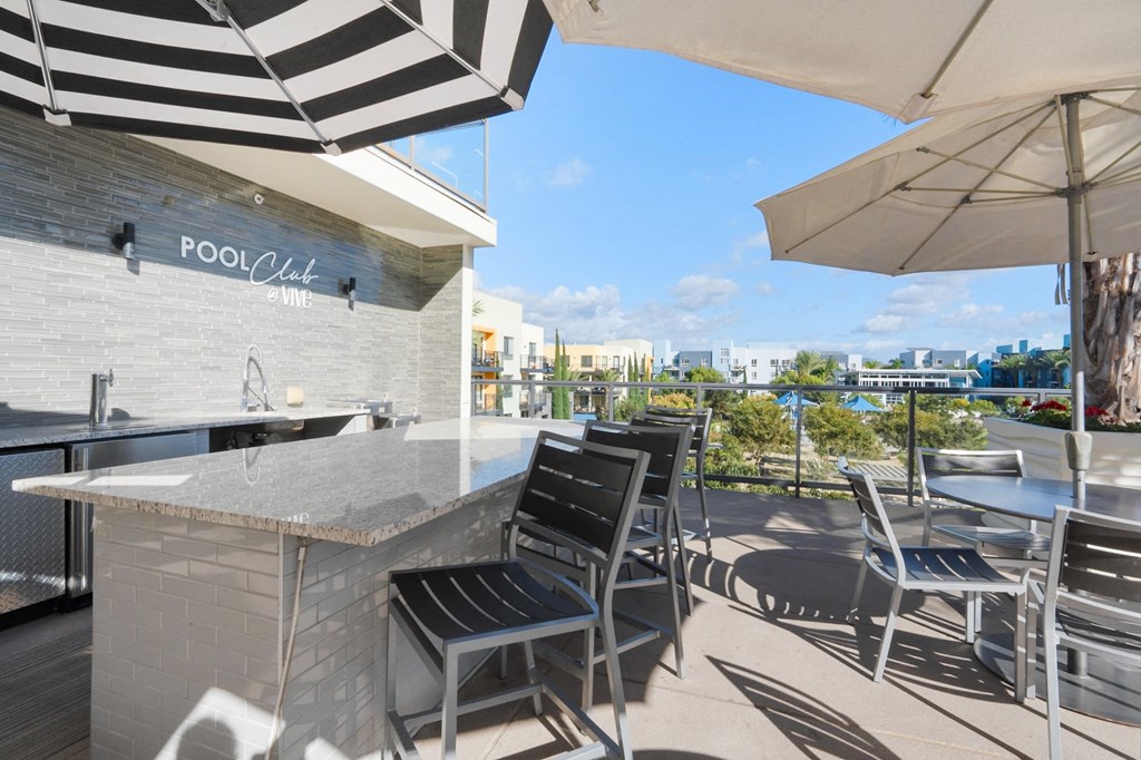 A pool bar with a striped umbrella and chairs.