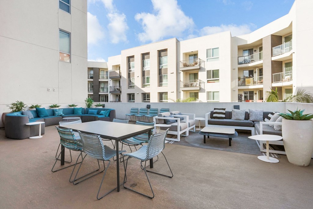 A patio with a table and chairs is surrounded by apartment buildings.