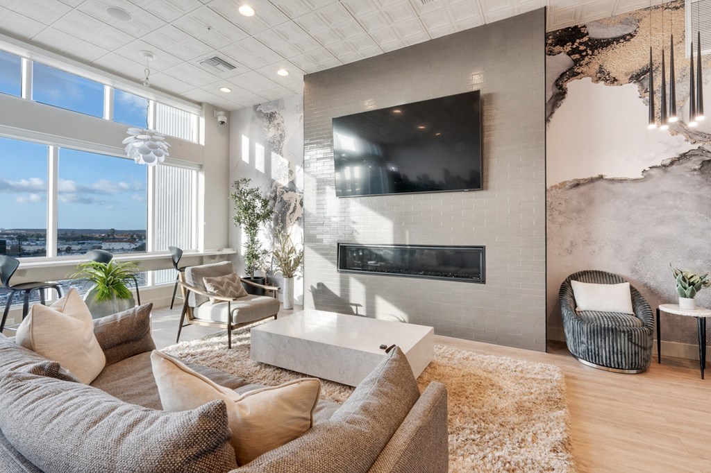 A modern living room with a large couch, a fireplace, and a flat-screen TV mounted on the wall.