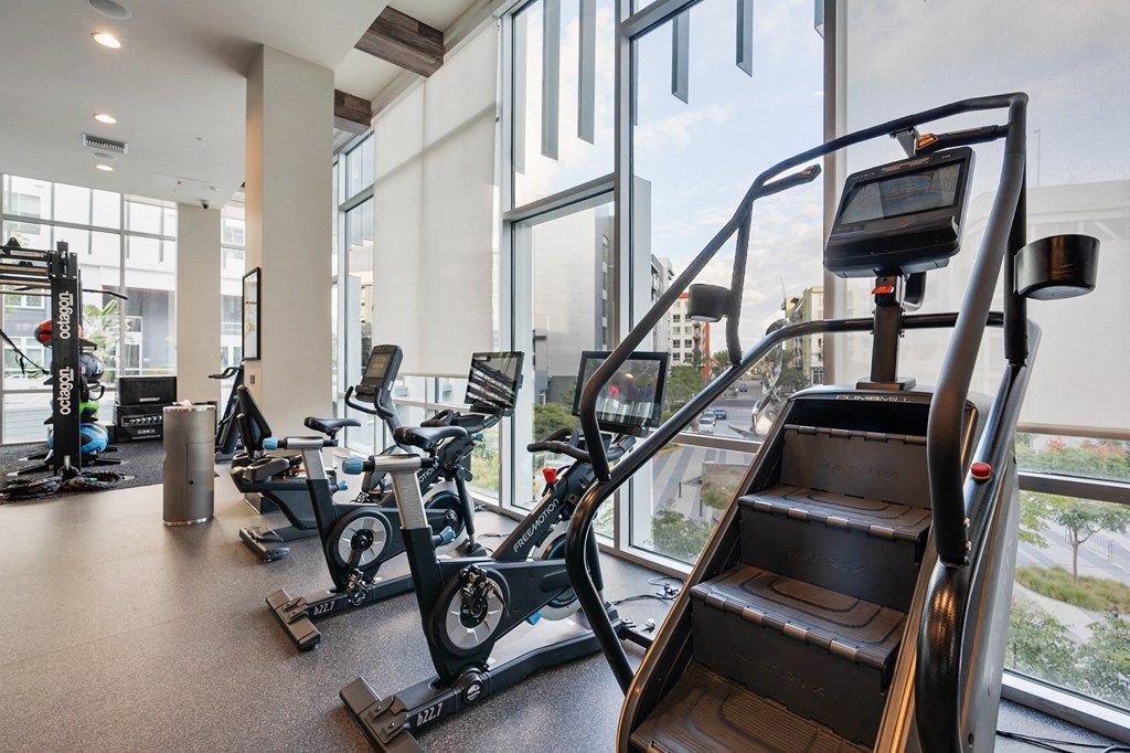 A gym with a treadmill, elliptical machines and a stair climber.
