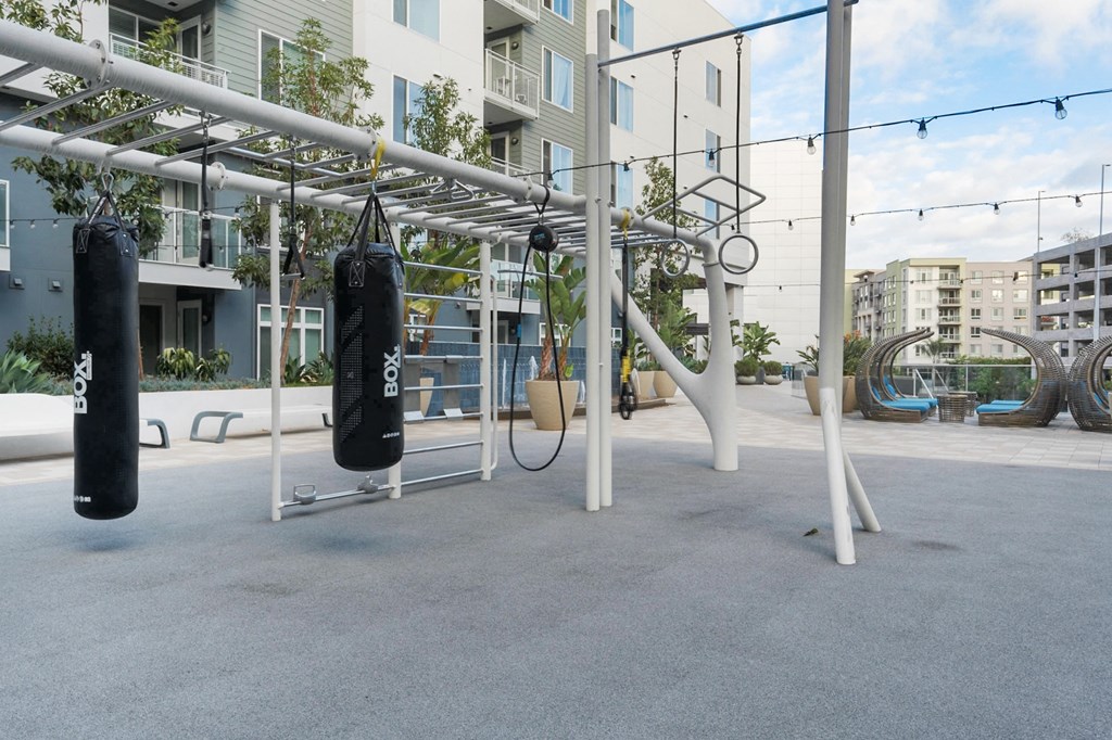 A gym setup with punching bags and rings in front of apartment buildings.