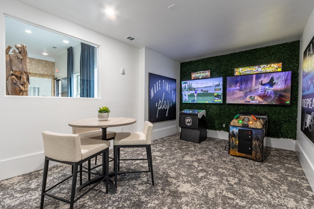 a lounge area with a table and chairs and televisions