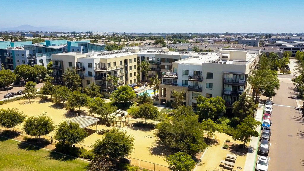 an aerial view of an apartment complex with a playground and cars parked in the parking lot