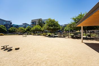 a large sandy area with a playground and picnic tables