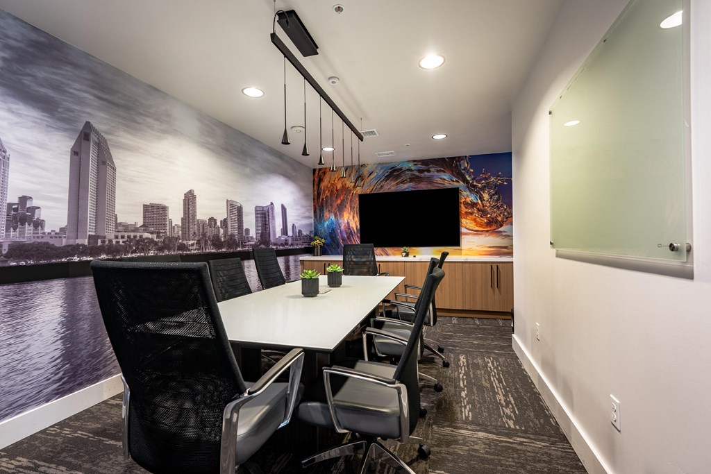 a meeting room with a large screen tv and a long table with chairs