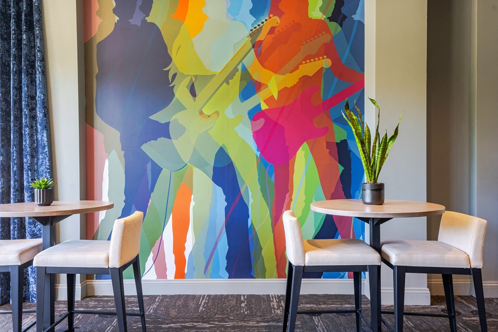 a large colorful mural with four tables and chairs in front of it