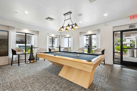 A pool table is in the middle of a room with a chair and a lamp.
