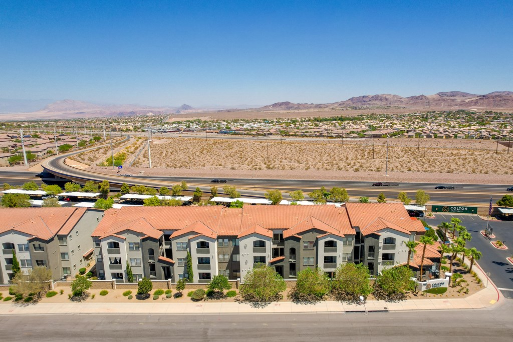 an aerial view of a group of apartment buildings with a freeway in the background