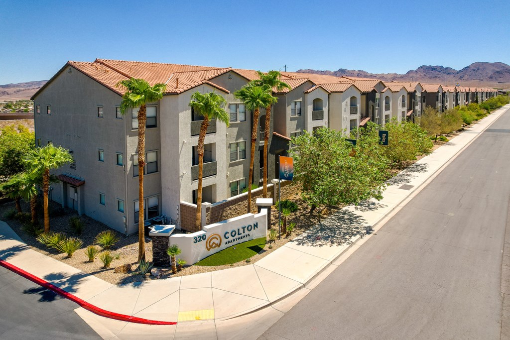 a row of apartment buildings with palm trees in front of a street