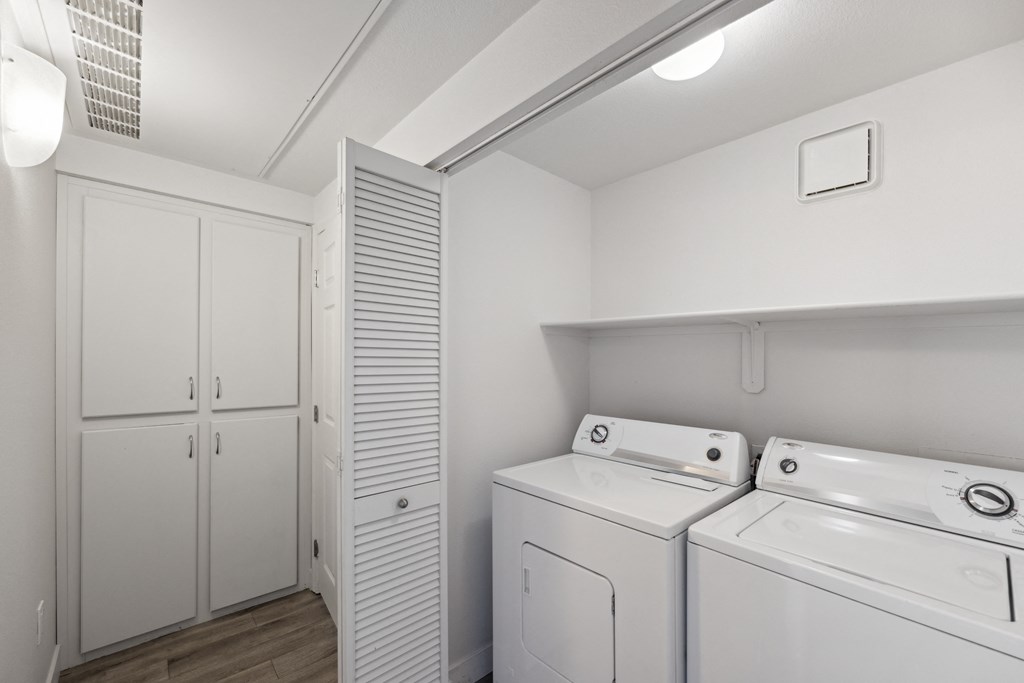 a white laundry room with white appliances and a white closet