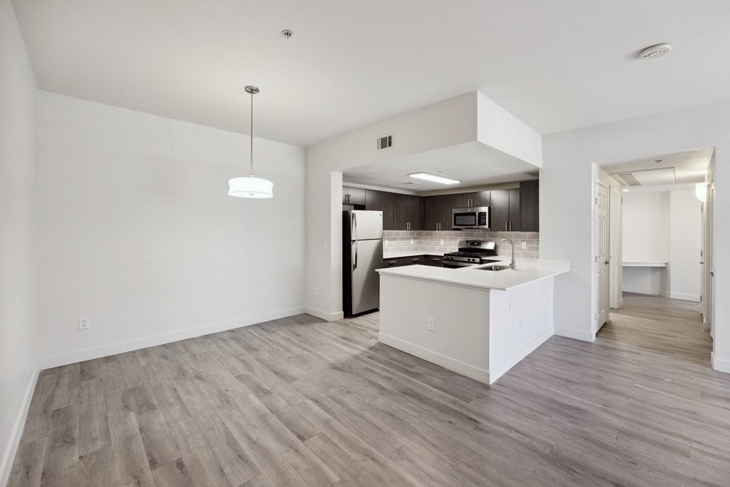 an empty living room and kitchen with white walls and wood flooring