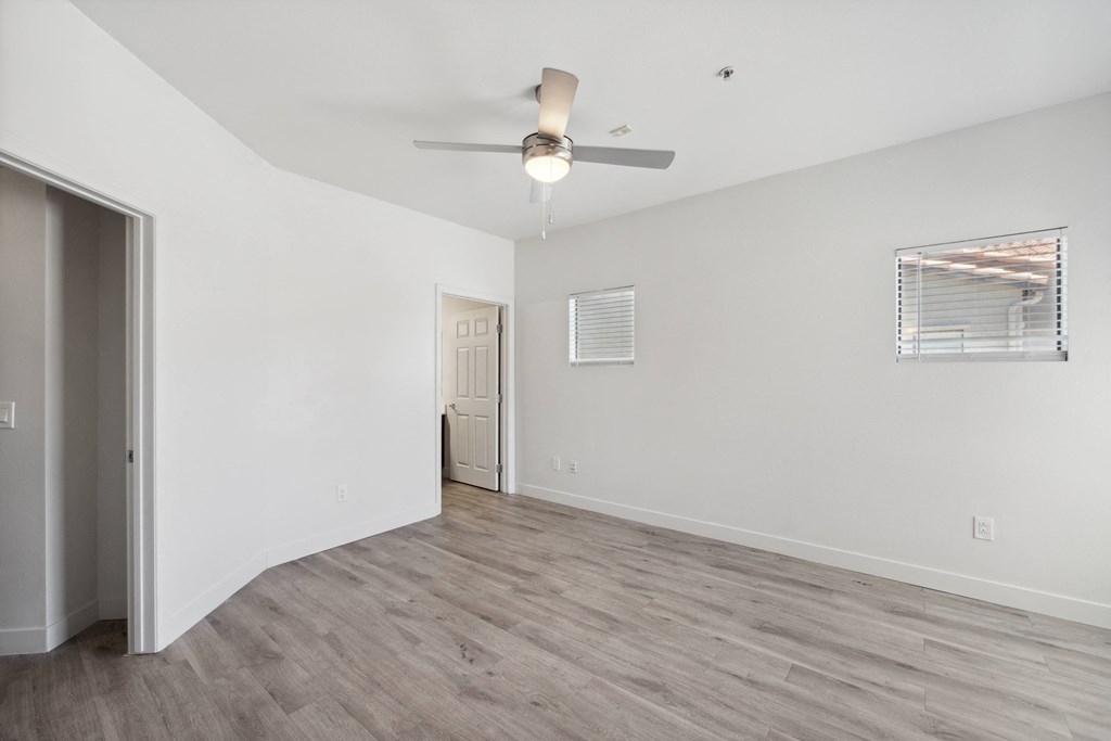 an empty living room with white walls and a ceiling fan