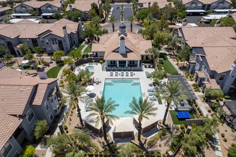 an aerial view of a swimming pool surrounded by houses and palm trees