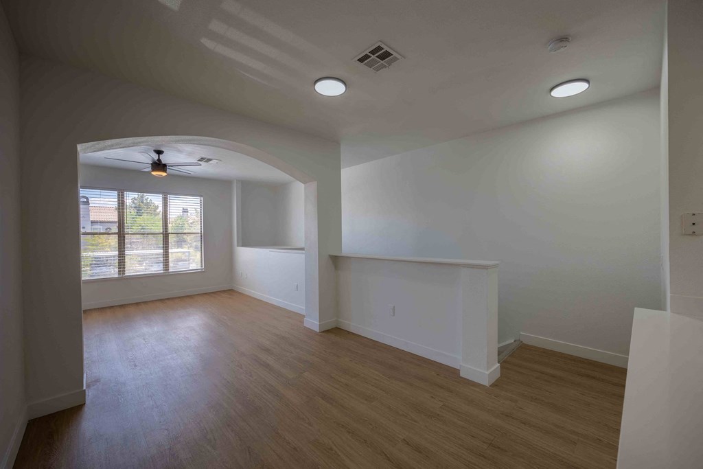 an empty living room with a ceiling fan and a window