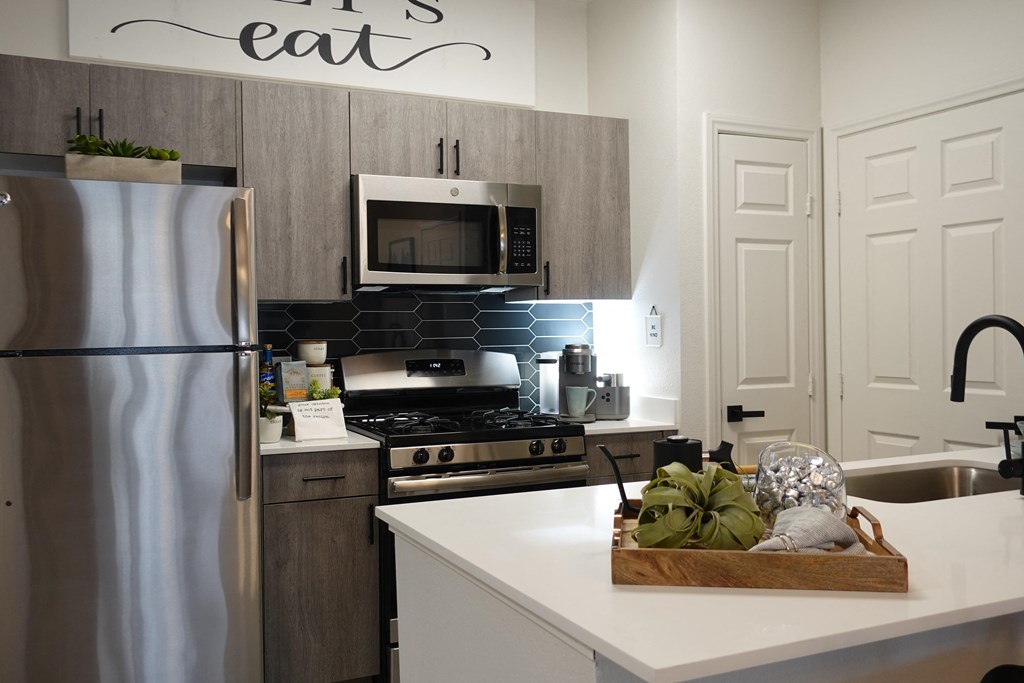 a kitchen with stainless steel appliances and a counter with a basket of food on it