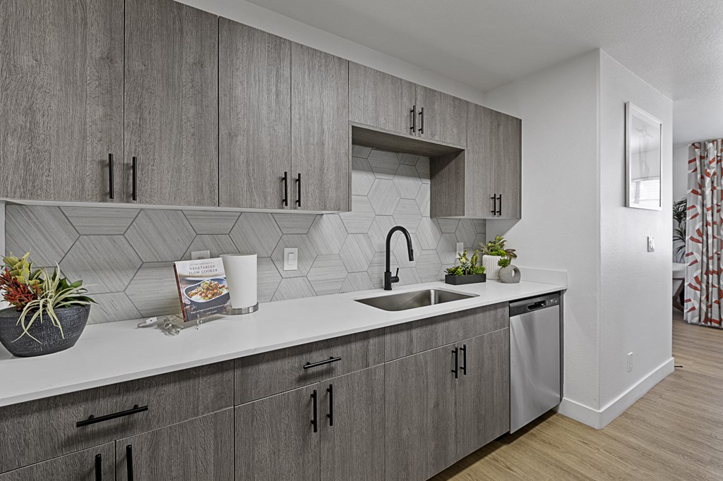 a kitchen with white countertops and gray cabinets and a sink