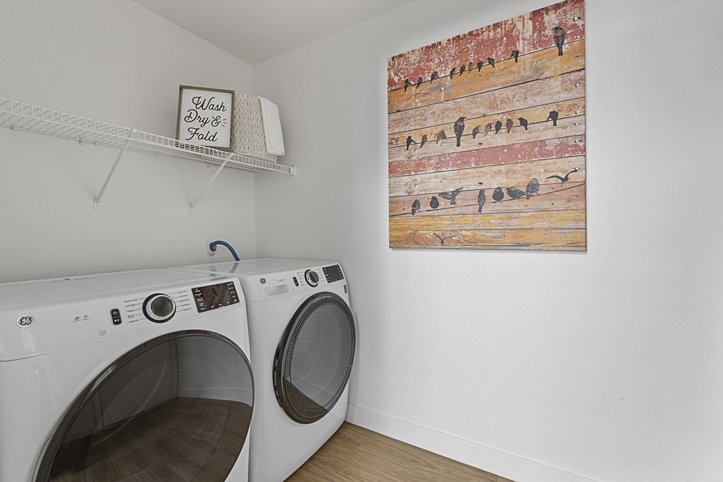 a washer and dryer in a laundry room with a painting on the wall