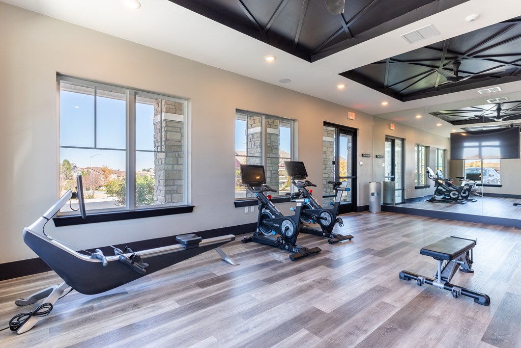 a gym with treadmills and weights on a wooden floor