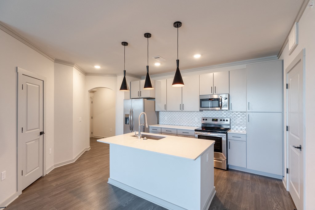 a kitchen with white cabinets and a white island with a sink