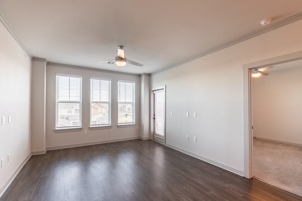 an empty living room with a ceiling fan and windows