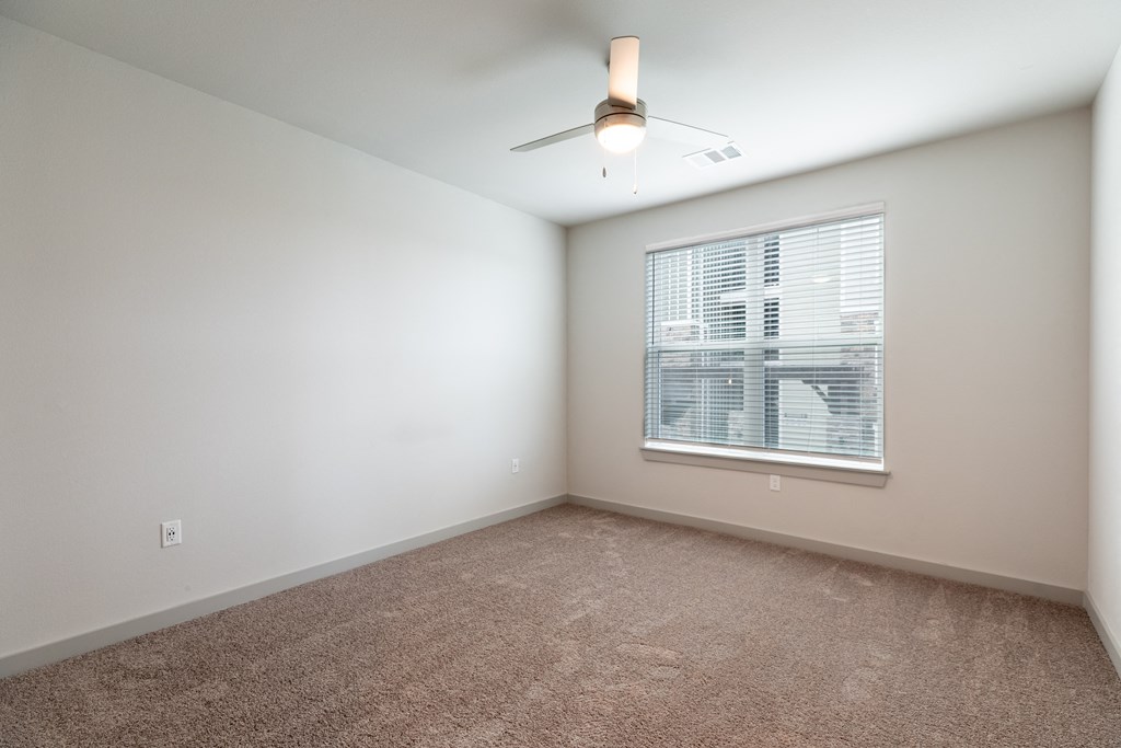 an empty room with a window and a ceiling fan