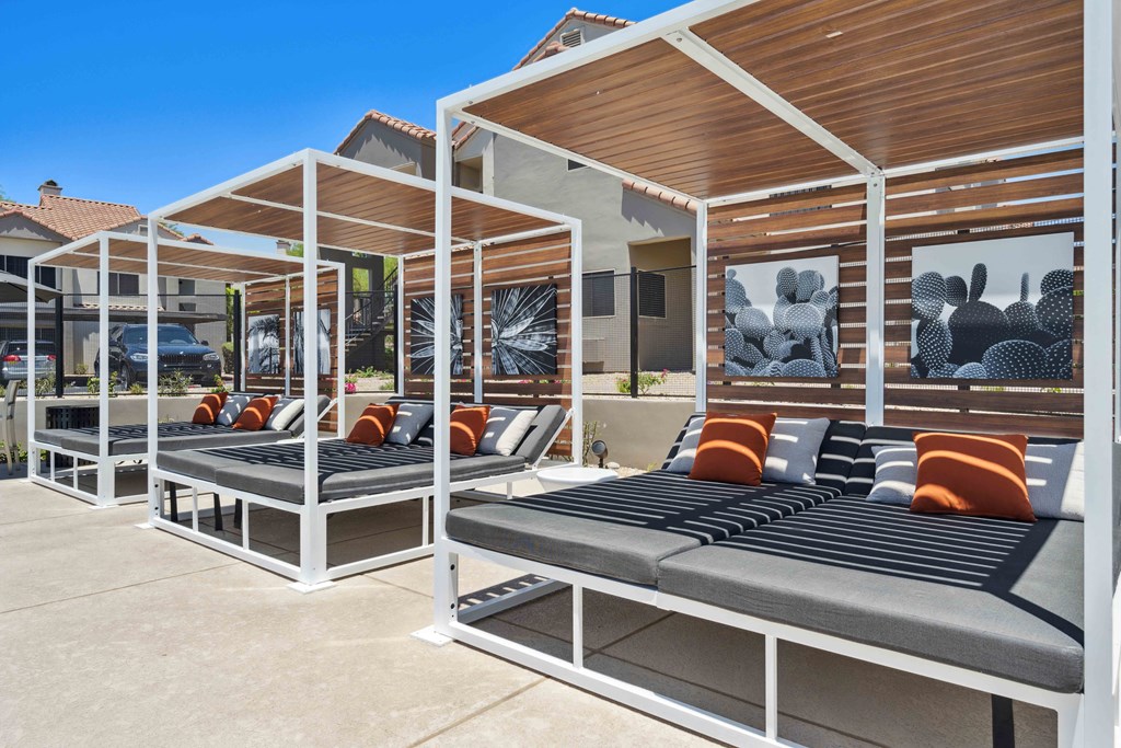 a row of white cabanas with orange and black pillows