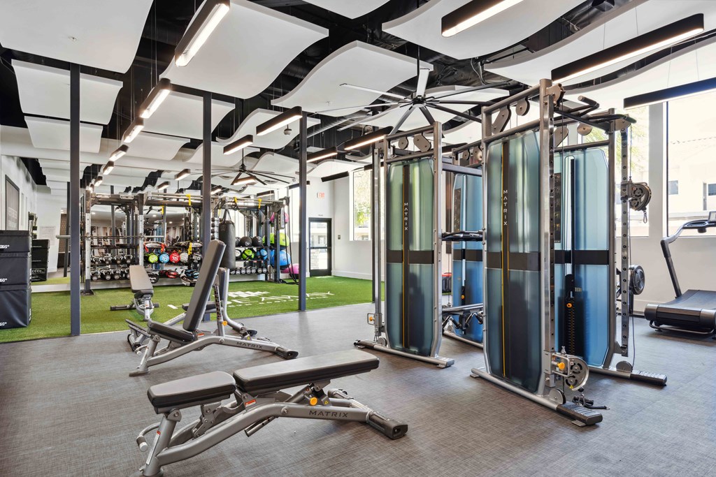 a spacious fitness center with benches at apartment community