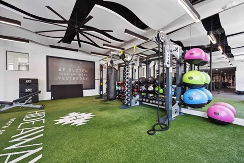A gym with a green floor and a sign that says "Be better than you were yesterday".