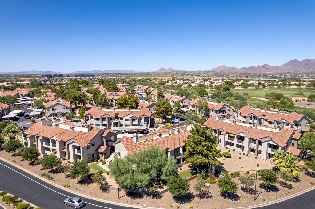 an aerial view of a neighborhood of houses with trees and mountains in the background