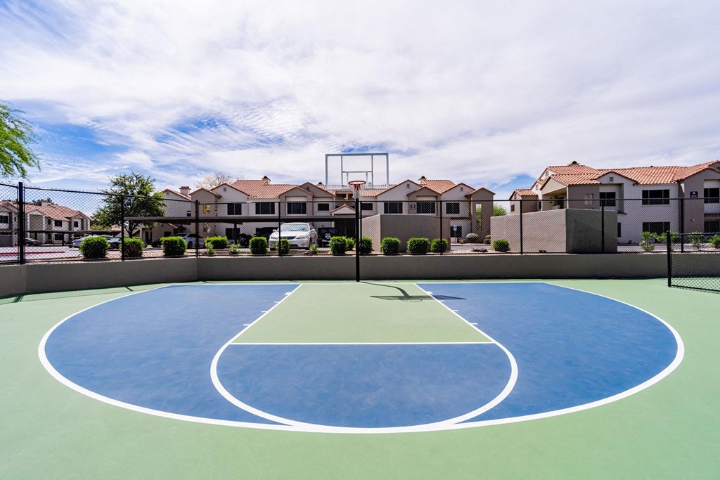 an outdoor basketball court with houses in the background