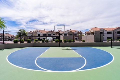 an outdoor basketball court with houses in the background