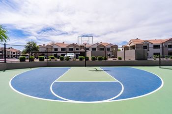 an outdoor basketball court with houses in the background