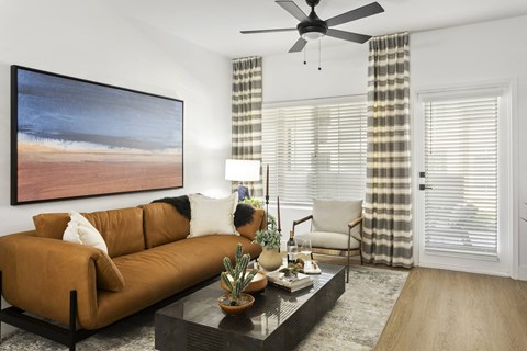 a living room with a brown couch and a ceiling fan