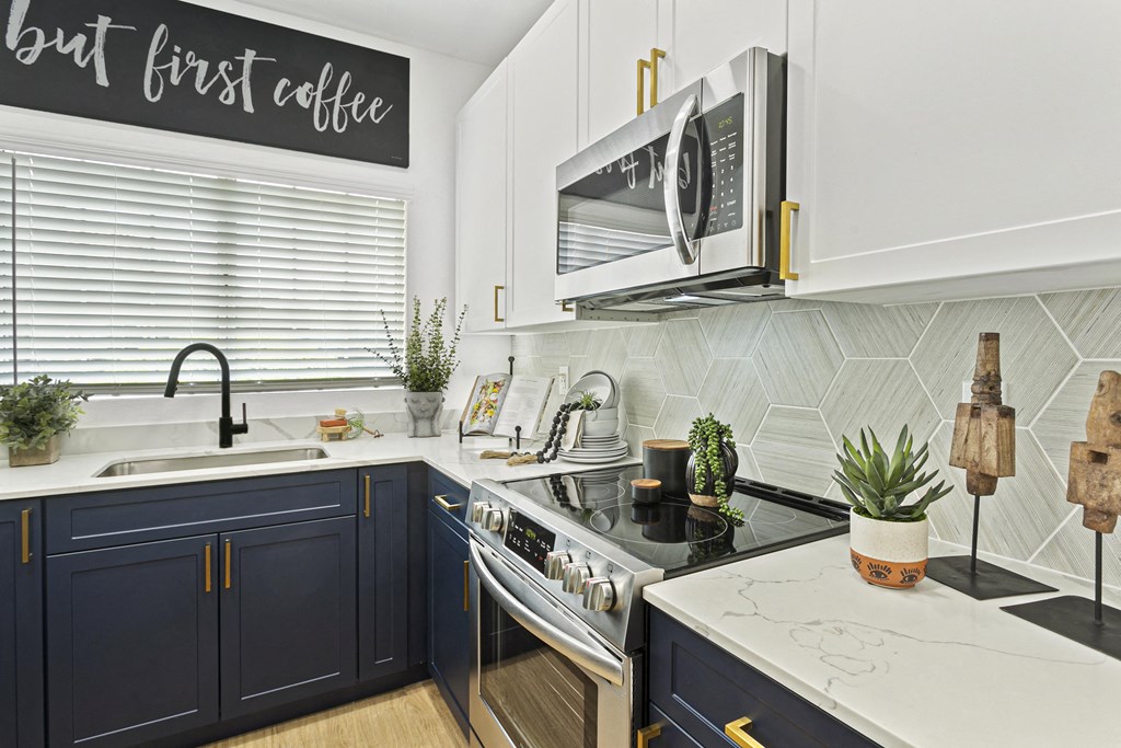 a kitchen with black and white cabinets and a sink and a microwave