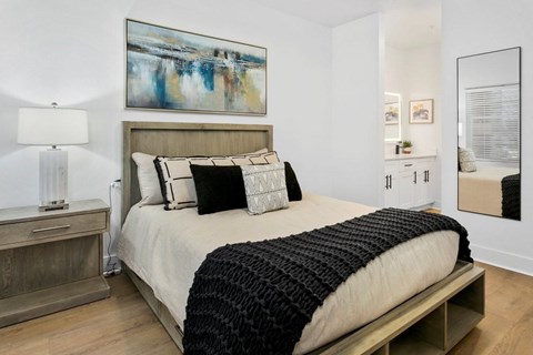 A bedroom with a large bed and a painting on the wall.