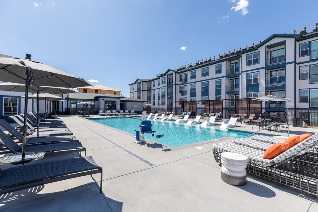 a swimming pool with lounge chairs and umbrellas at the cardinal apartments