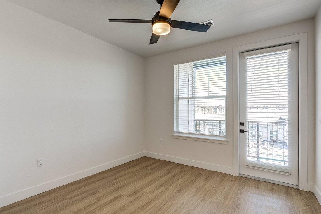 an empty living room with a ceiling fan and a window