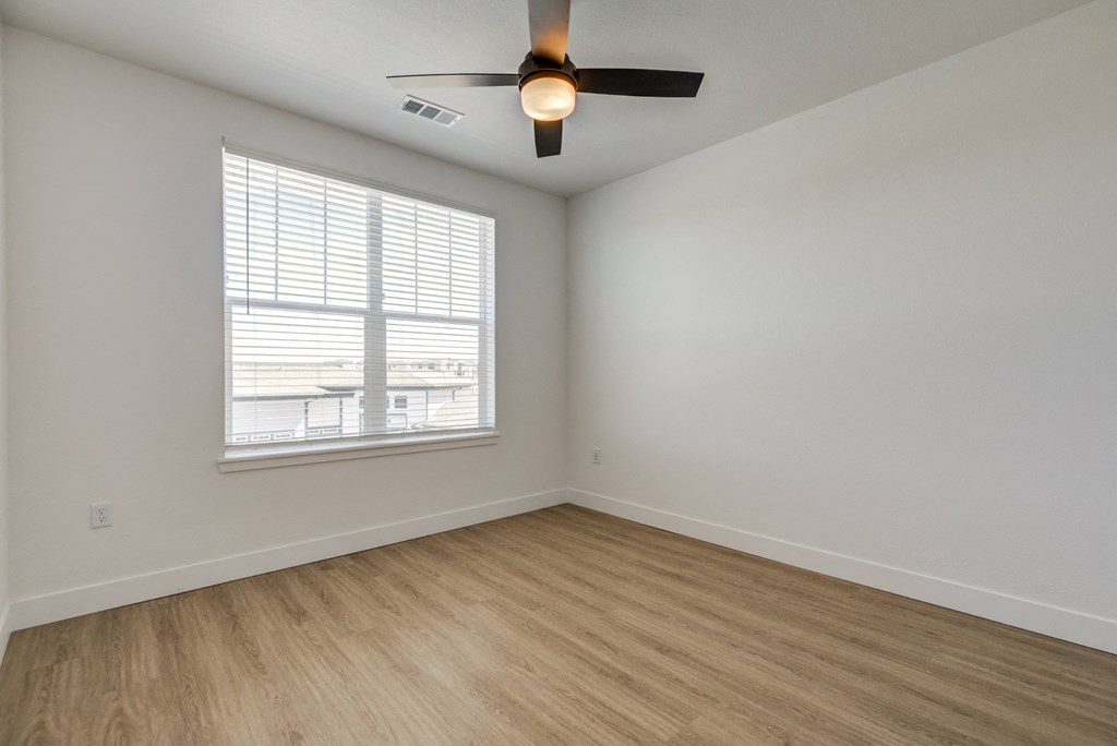 an empty room with a ceiling fan and a window