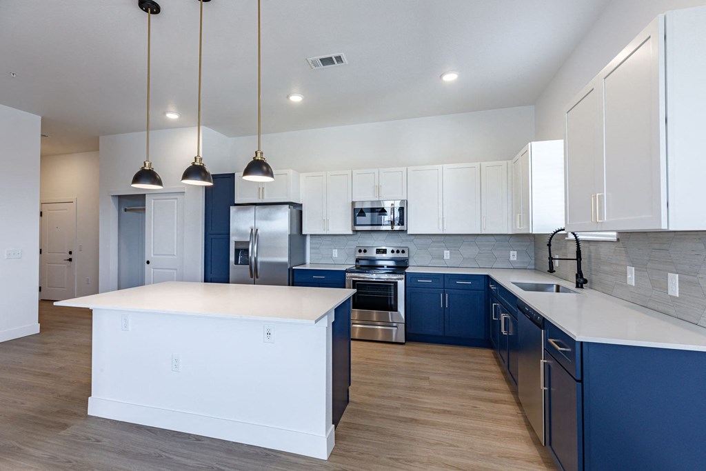 a large kitchen with blue and white cabinets and a white counter top