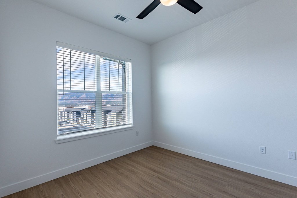 hardwood style flooring with ceiling fan in bedroom with large window at Jasper at Victory Ridge in CO