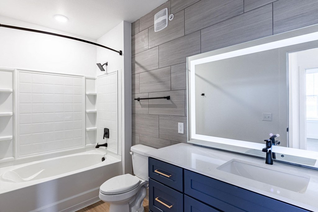 a bathroom with a large mirror and a toilet and a tub