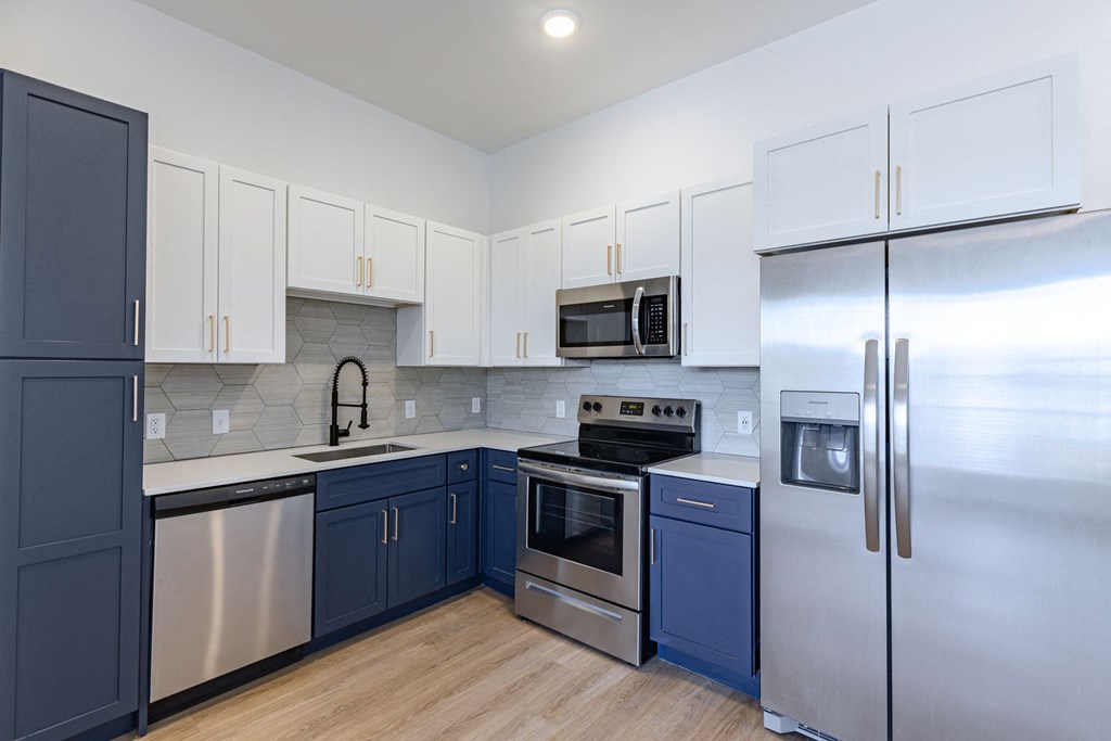 a kitchen with stainless steel appliances and blue and white cabinets