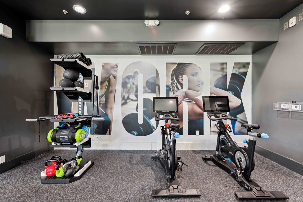 a gym with exercise equipment in front of a wall of ads