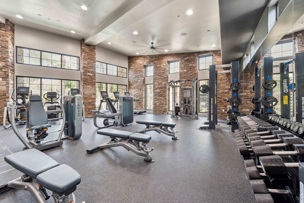 a gym with weights and cardio equipment and windows
