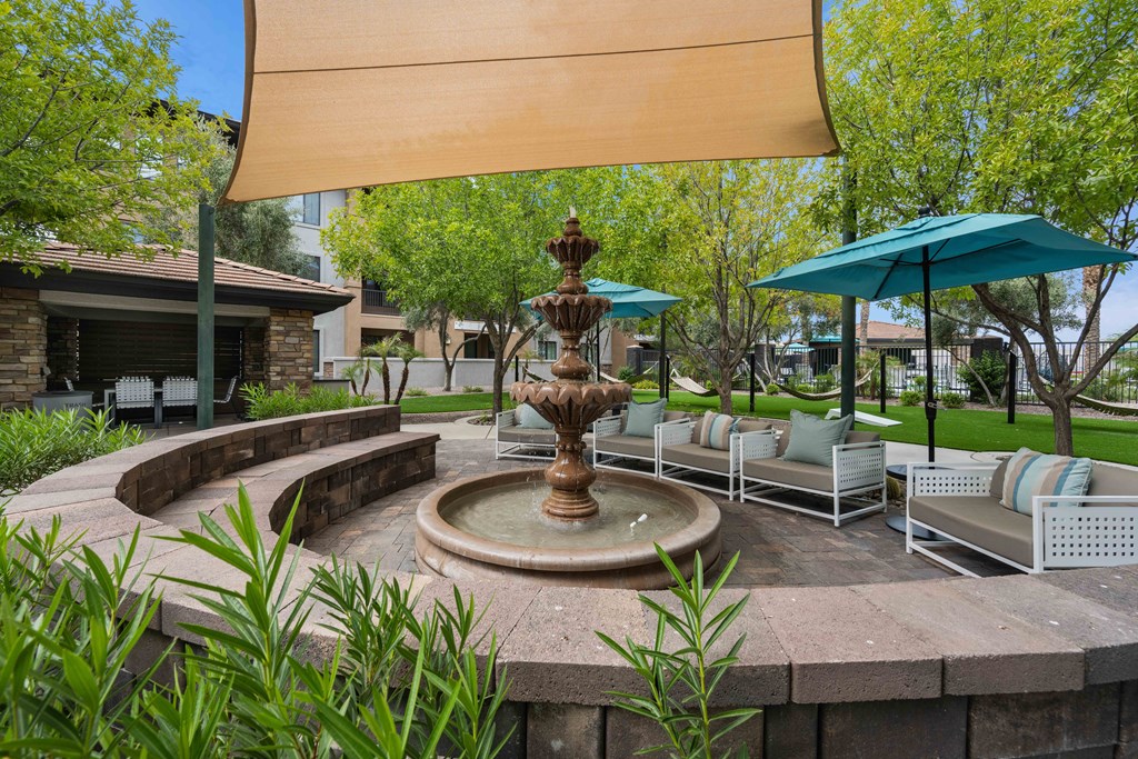 a fountain in the middle of a patio with chairs and umbrellas