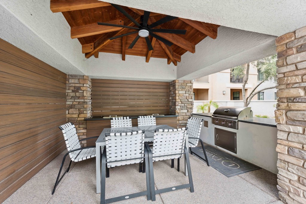 a dining area with a table and chairs and a barbecue grill